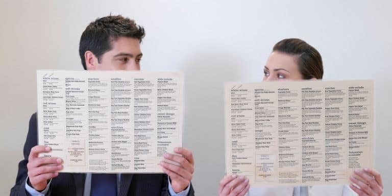Two people reading a long menu