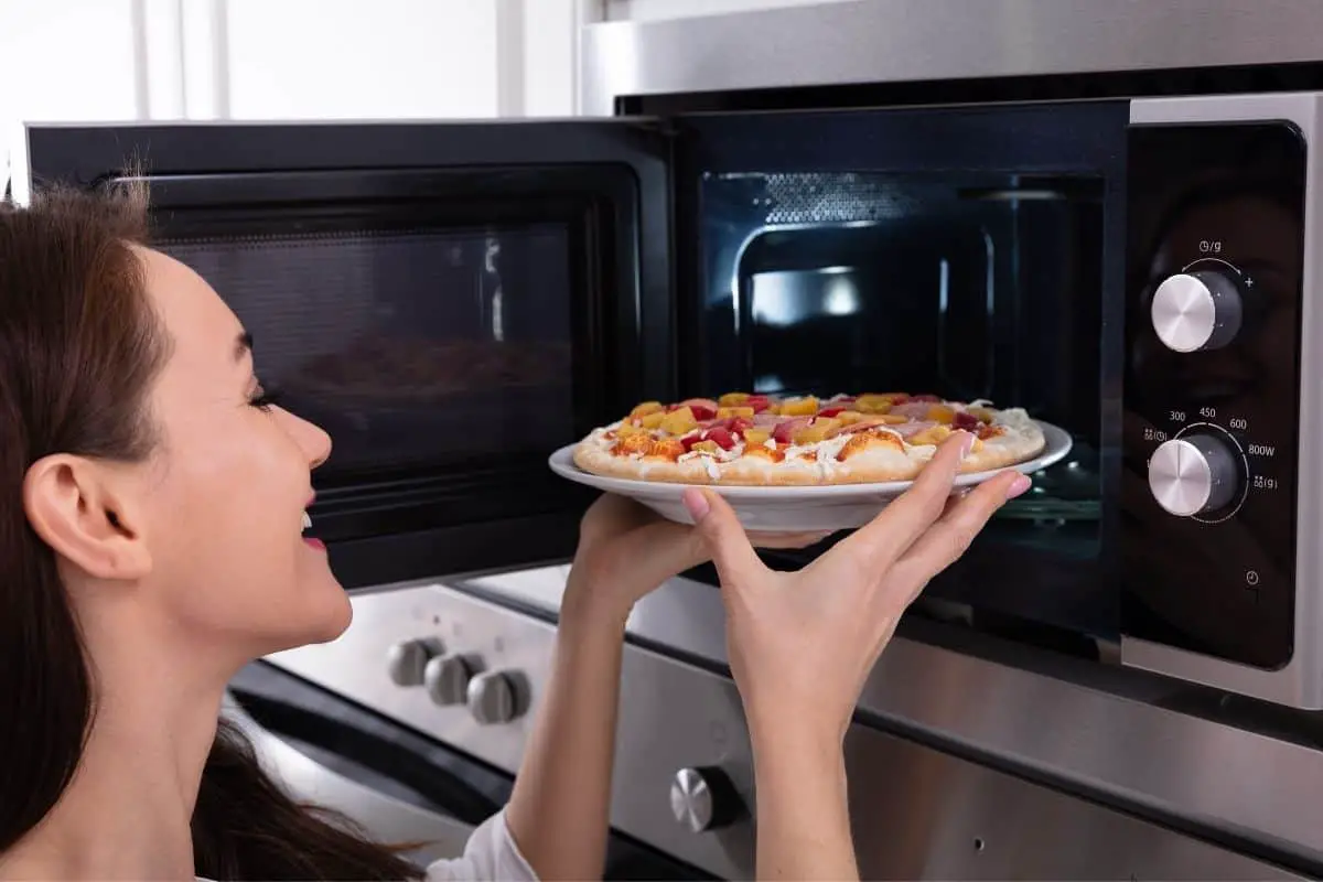 Woman heating pizza in microwave