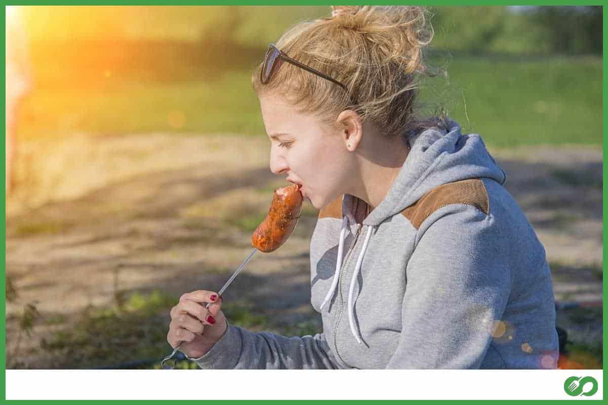 Girl eating sausage from the grill